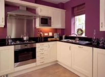 Кухня с Г-образной мебелью. Стены фиолетовые, столешница черная, корпус бледно-бледно-розовый